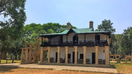 Dhela Forest Rest House building with a safari jeep parked outside